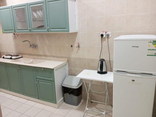 麦地那شقق الفتح الخاصة Al-Fateh Private Apartments的厨房配有绿色橱柜、水槽和冰箱。