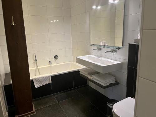 Onstwedde德海丁霍夫酒店的浴室配有盥洗盆和浴缸。
