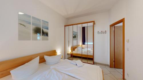 宾茨Villa Strandburg的一间卧室配有一张带白色床单和镜子的床