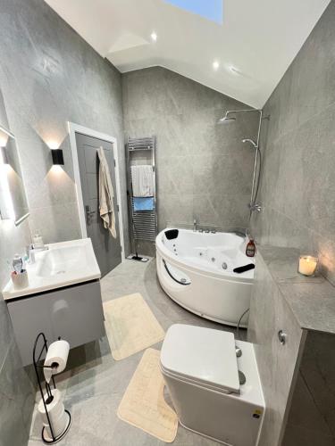 格林福德Cozy Luxury Private Cottage的带浴缸、卫生间和盥洗盆的浴室