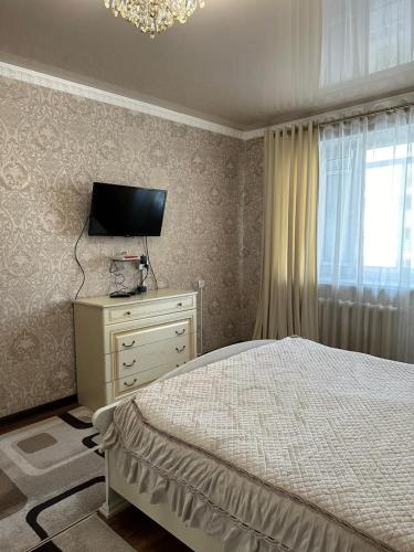 塔拉兹Квартира люкс的一间卧室配有一张床、一台电视和一个窗口
