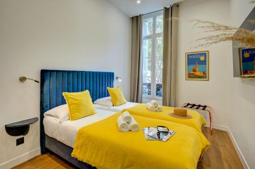 马赛Boutique Hôtel Provencia的一间卧室配有两张带黄床单的床