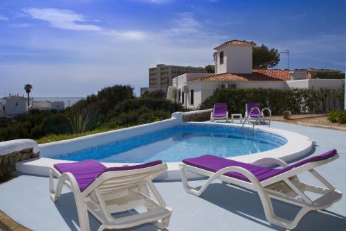 卡拉恩·布拉內斯Apartamentos Blue Beach Menorca的一个带2把躺椅的游泳池和一个游泳池