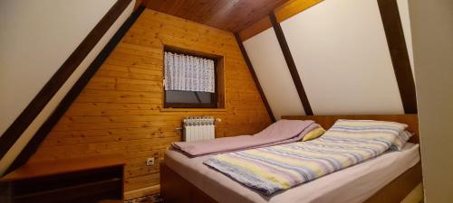 亚霍里纳Vjeverica Chalet的木制客房的一张小床,设有窗户