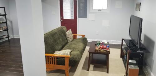 华盛顿English Basement Suite in Petworth, Washington, DC -- FREE off-street parking, walk to Metro and restaurants的客厅配有绿色沙发和电视