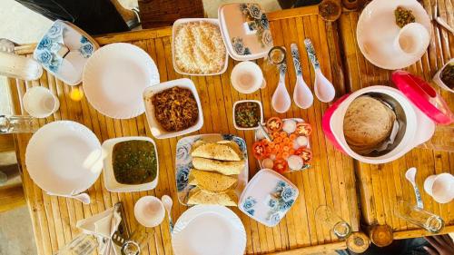 KhāpaAthulyam Kanha, kanha national park, mukki gate的木桌,上面放有盘子和碗的食物