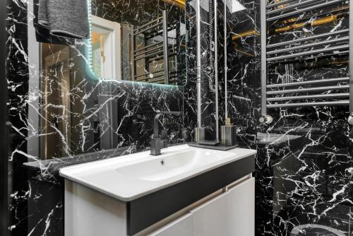 伊斯坦布尔Nil Denis Palace的浴室设有白色水槽和黑色大理石墙壁。