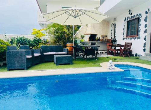 伊科德洛斯维诺斯Pintadera house Caracola的一个带庭院家具和遮阳伞的游泳池