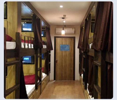 孟买Hilal dormitory的走廊设有三张双层床和一扇门