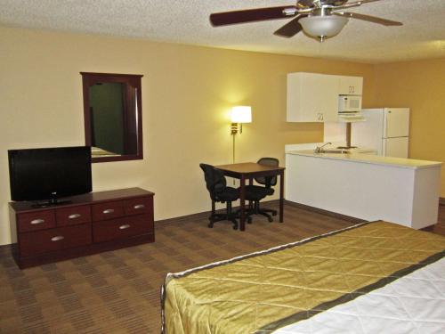 罗利Extended Stay America Suites - Raleigh - Midtown的酒店客房设有一张床铺、一张桌子和一间厨房。