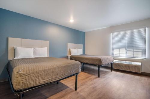费耶特维尔Extended Stay America Select Suites - Fayetteville的配有两张床铺的蓝色墙壁和窗户