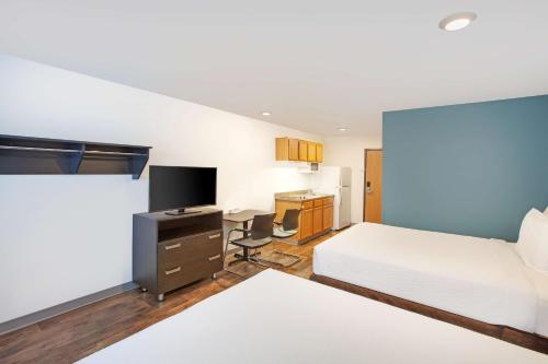 拉斯克鲁塞斯Extended Stay America Select Suites - Las Cruces的一间卧室配有一张床和一张书桌及电视