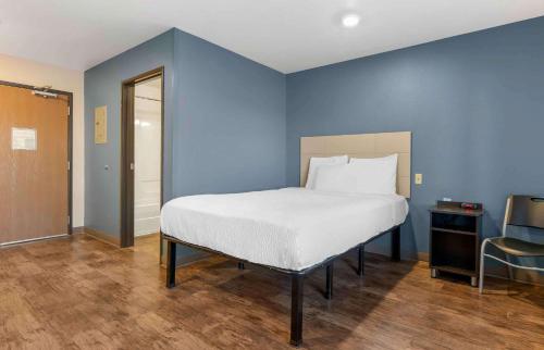 奥兰多Extended Stay America Select Suites - Orlando - South的蓝色卧室,配有床和椅子