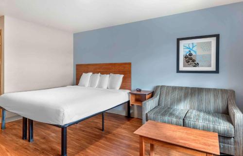 威奇托Extended Stay America Select Suites - Wichita - Airport的一间卧室配有一张床、一把椅子和一张沙发
