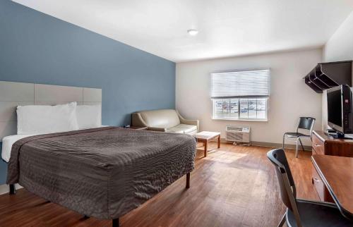 威奇托Extended Stay America Select Suites - Wichita - South的一间卧室配有一张床、一把椅子和电视