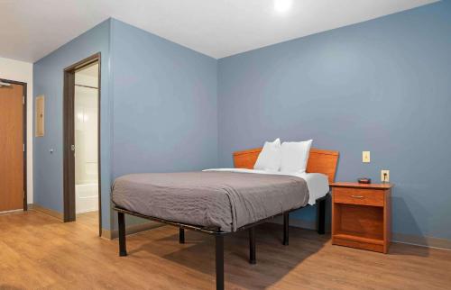 沃尔顿堡滩Extended Stay America Select Suites - Fort Walton Beach的一间卧室设有一张床和蓝色的墙壁