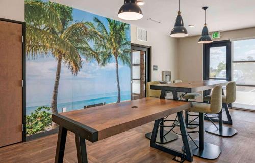 West MelbourneExtended Stay America Premier Suites - Melbourne - Palm Bay的一间设有桌子和棕榈树壁画的用餐室