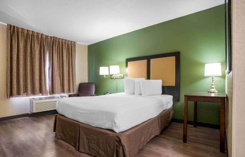 彭萨科拉美国 - 彭萨科拉 - 大学城长住旅馆的酒店客房设有一张大床和绿色的墙壁。