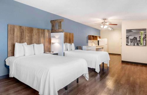 迈阿密Extended Stay America Premier Suites - Miami - Airport - Doral - 87th Avenue South的一间卧室配有两张床,配有白色的床单和蓝色的墙壁