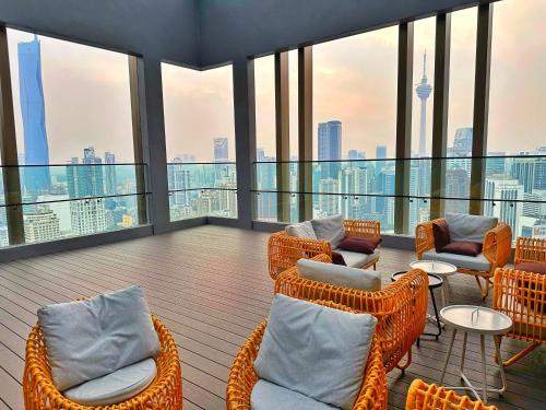 吉隆坡Axon Residence Bukit Bintang By TR Suites的阳台设有藤椅、桌子和窗户。