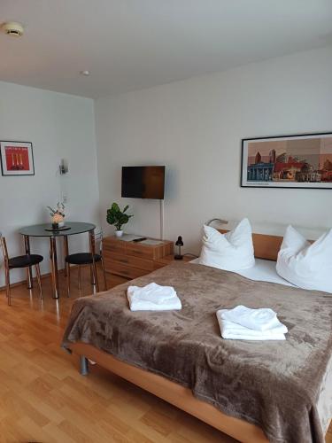柏林商务公寓的一间卧室配有一张床、一张桌子和一台电视
