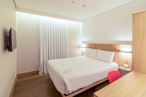 阿雷格里港Hotel Moov Porto Alegre的卧室配有白色的床、书桌和椅子