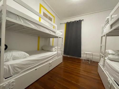 波尔图Owls Hostel的一间卧室设有两张双层床,铺有木地板。