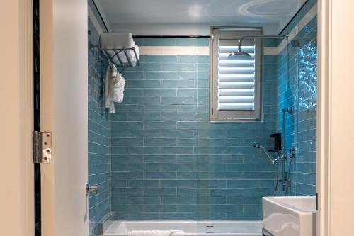 迈阿密海滩Nassau Suite South Beach, an All Suite Hotel的浴室配有蓝色瓷砖浴缸和水槽。