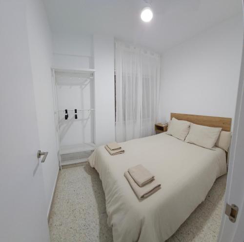 卡拉瓦卡·德·拉·克鲁斯Apartamento Gómez的白色卧室配有一张大床和毛巾