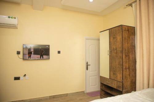 阿布贾Bott Extended Stay的卧室在床边的墙上配有电视