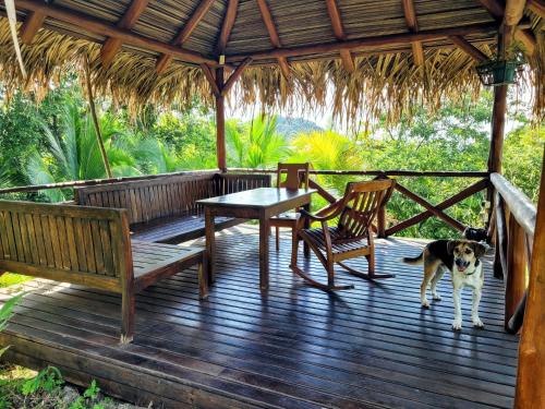 萨玛拉Villa Martina Palmgarden的一只狗站在木甲板上,配有桌椅