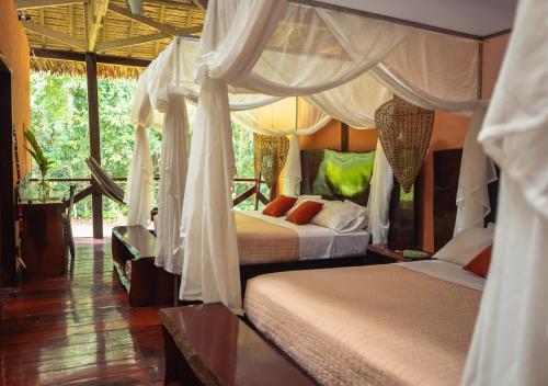 TambopataRefugio Amazonas Lodge的一间卧室配有两张床和一张天蓬床。