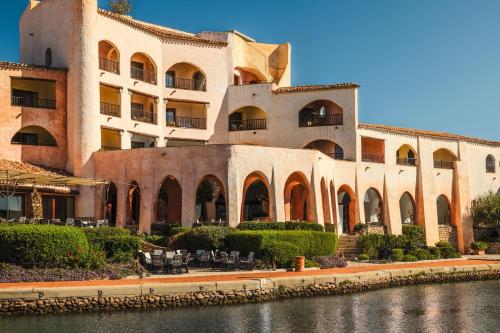 切尔沃港Hotel Cala di Volpe, a Luxury Collection Hotel, Costa Smeralda的前面有一条河流的大建筑