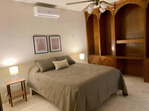 埃莫西约Casa Tehuantepec, 5hab 4.5baños的一间卧室配有一张带两张桌子的床和吊扇。