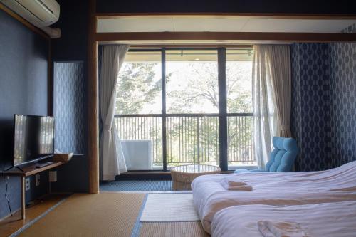 伊东ISOLA Izukogen的酒店客房设有一张床和一个大窗户