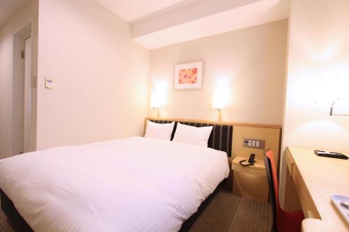 仙台KOKO HOTEL Sendai Station West的一间酒店客房,配有一张白色的床和一张书桌