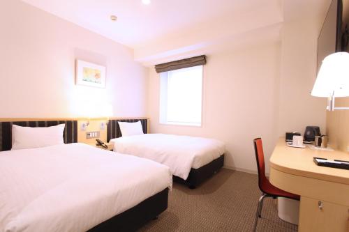 仙台KOKO HOTEL Sendai Station West的酒店客房配有两张床和一张书桌