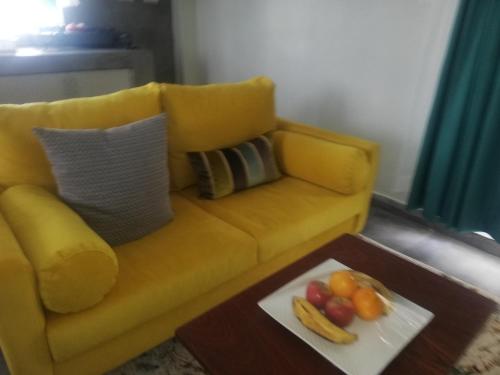 KakamegaCasa nostra的一张黄色的沙发,桌子上放着一盘水果