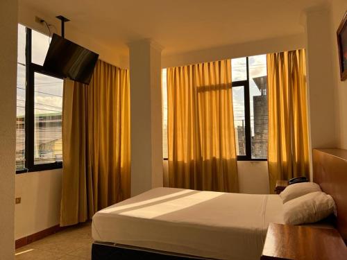 新洛哈Hotel King David Ecuador的一间卧室设有床和窗户,窗户配有黄色窗帘