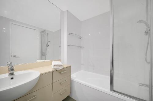 布里斯班布里斯班三部曲公寓式酒店的白色的浴室设有水槽和淋浴。