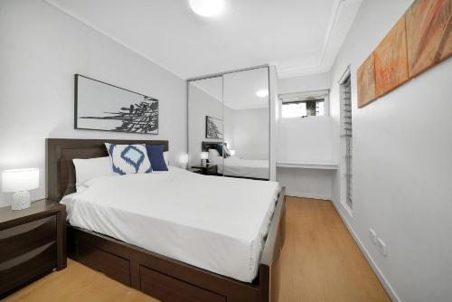 布里斯班布里斯班三部曲公寓式酒店的白色卧室配有床和镜子