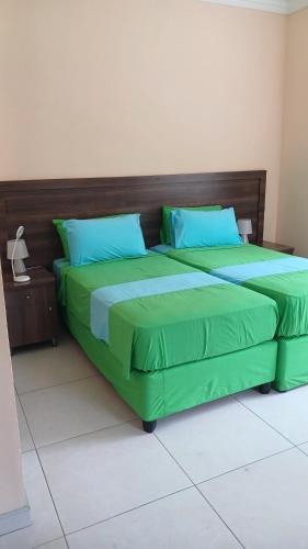 马埃岛贝拉扎尔区Beau Bassin Inn的一张带绿床单和蓝色枕头的床