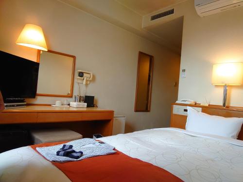 青森Aomori Green Park Hotel Annex的酒店客房配有一张床和一张带镜子的书桌