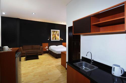 雅加达ARCS House Menteng by Jambuluwuk的酒店客房设有一张床和一个带水槽的厨房