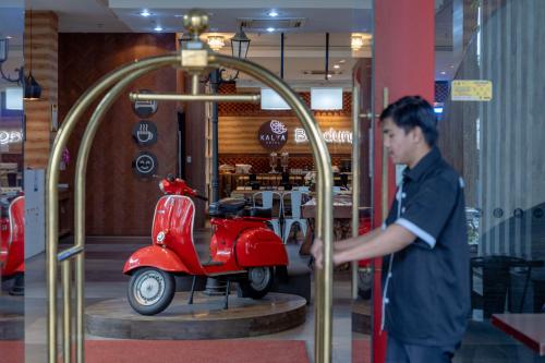 万隆Kalya Hotel Bandung Dago的一个人在商店里看一辆红色的摩托车