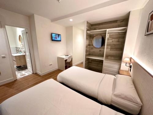 马德里格兰大道离家旅舍的一间卧室配有两张床和电视。