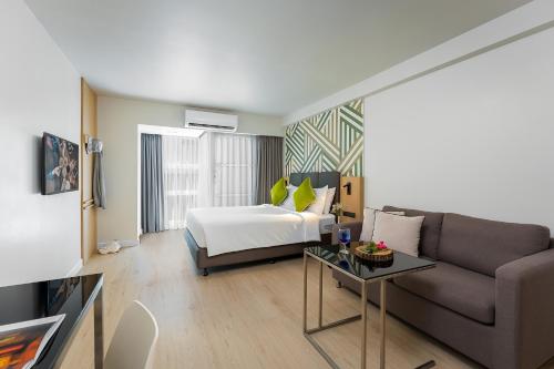 曼谷Citadines Sukhumvit 16 Bangkok的酒店客房,配有床和沙发
