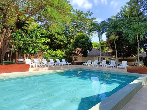 沙美岛Malibu Samed Resort的一个带白色椅子和树木的游泳池