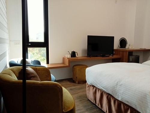 鹿港镇洛津驿民宿的一间卧室配有一张床、一台电视和一把椅子