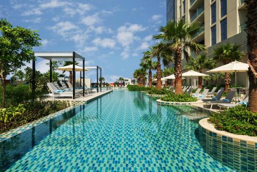 迪拜DAMAC Maison Aykon City Dubai的度假村的游泳池,配有椅子和遮阳伞
